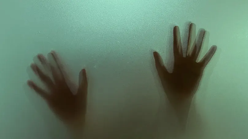 Une scène cauchemardesque de deux mains pressées sur du verre vert