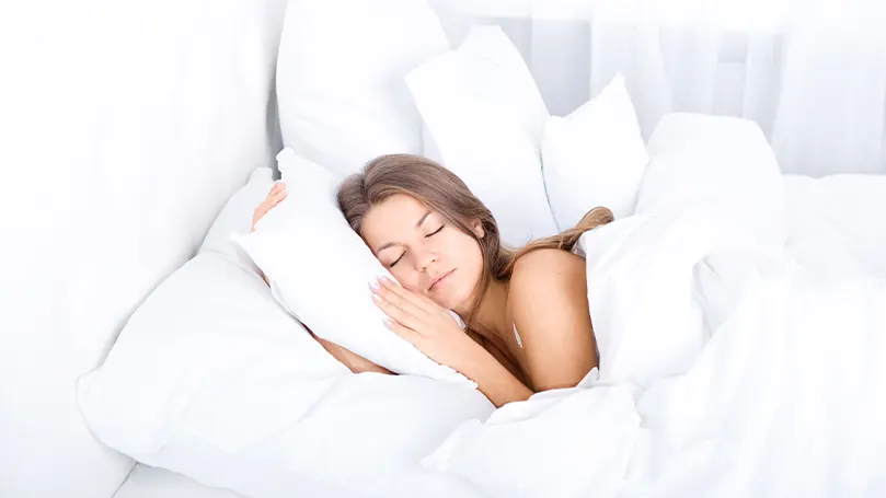 Image d'une femme dormant avec un grand nombre d'oreillers