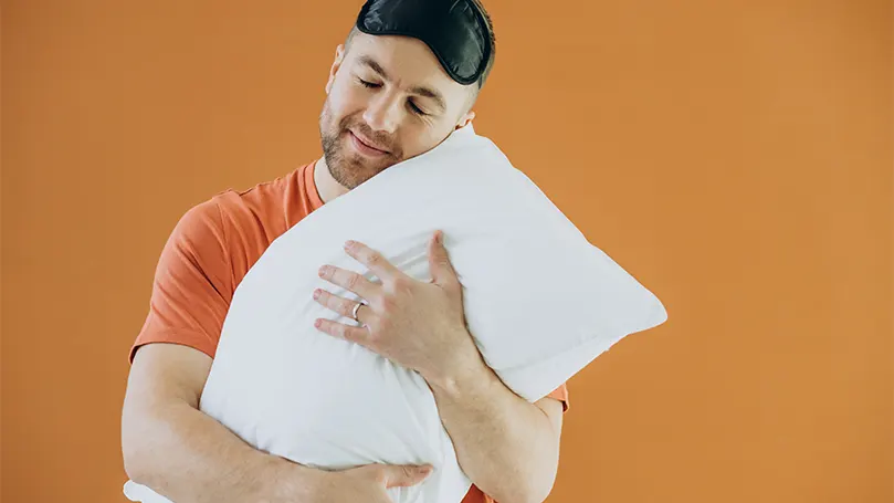 Image d'un homme serrant un oreiller dans ses bras