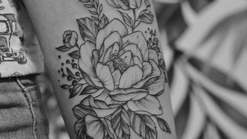 Image d'une personne dont le bras est recouvert d'un tatouage en forme de rose