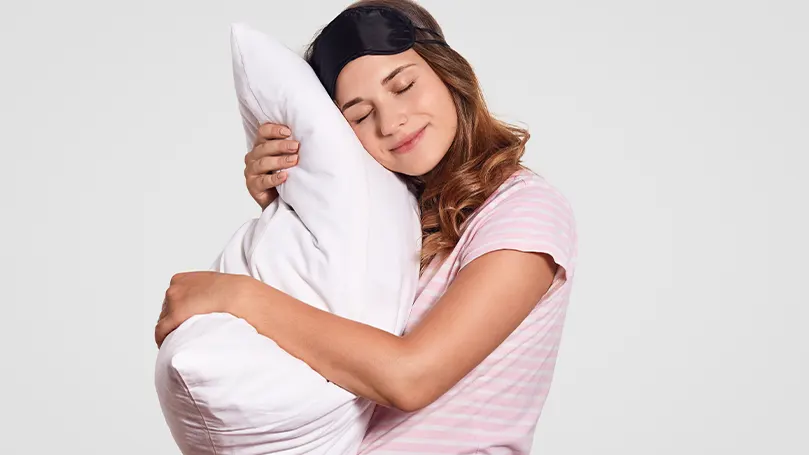 Image d'une femme serrant son oreiller dans ses bras