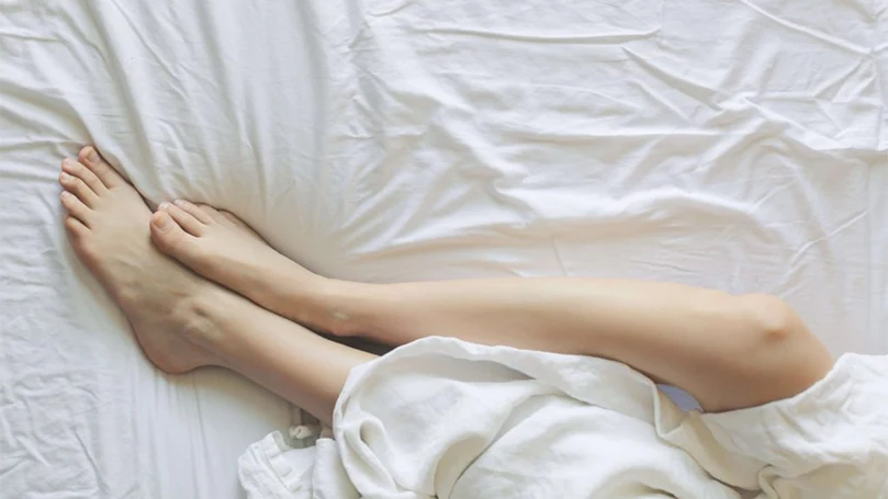 une femme allongée sur des draps dans un lit