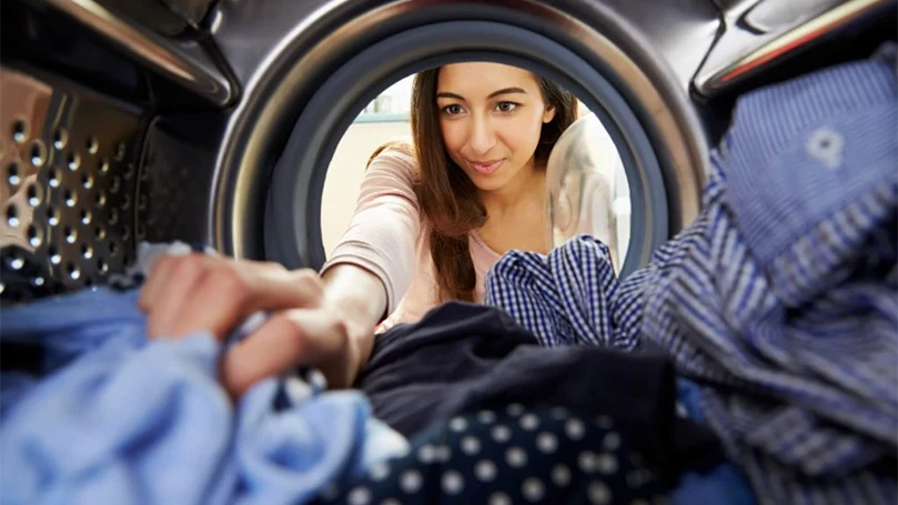 une image d'une femme mettant des vêtements dans la machine à laver