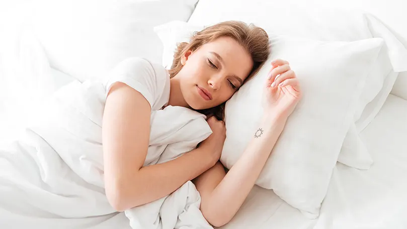 Image d'une femme dormant confortablement sous une couette chaude.