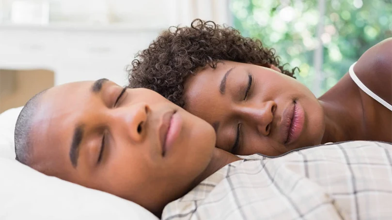 une image d'un couple dormant confortablement dans un lit