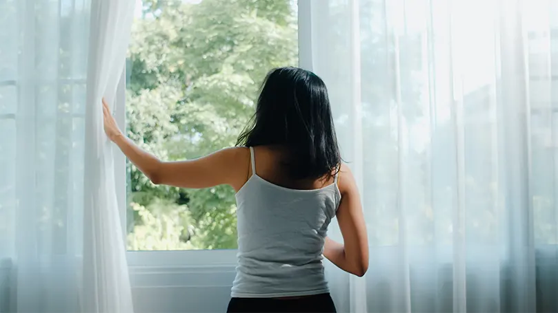 Image d'une femme ouvrant la fenêtre et laissant entrer l'air frais