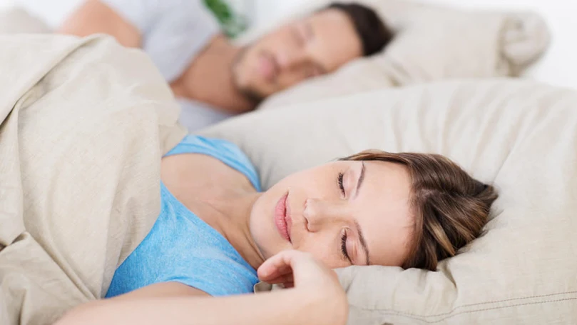 une image d'un couple dormant dans un lit