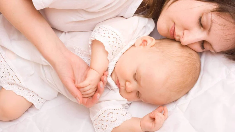 une image d'une mère dormant avec un bébé