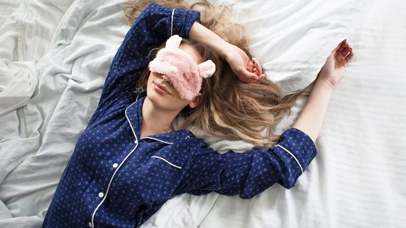 une femme dormant avec un masque pour les yeux sur le dos