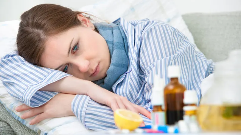 une femme en pyjama à côté d'un médicament contre le rhume
