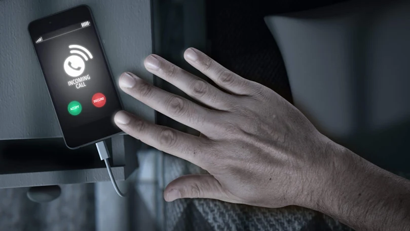une image d'une main laissant un smartphone sur une table de nuit
