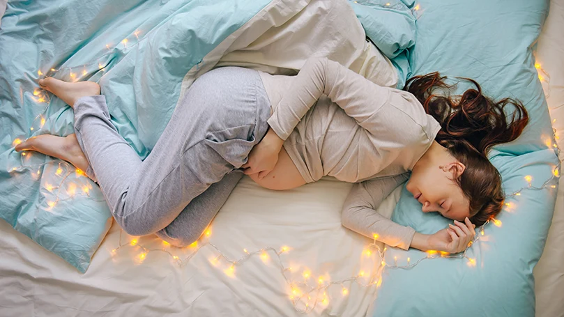 l'image d'une femme enceinte dormant dans un lit avec la lumière allumée