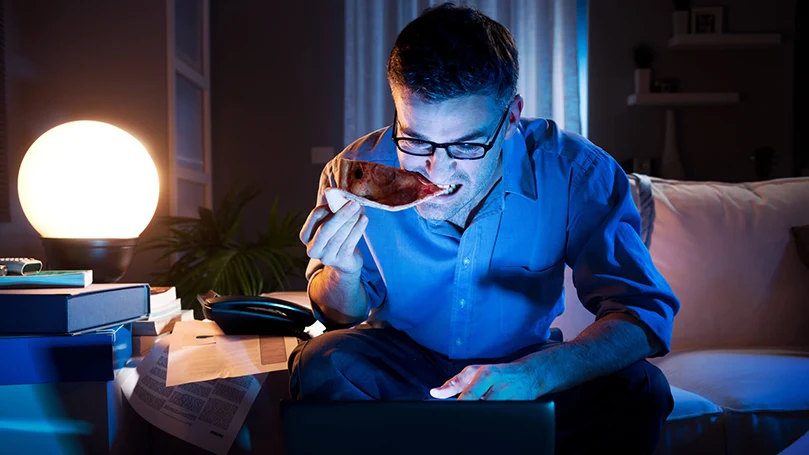 un homme travaillant sur un ordinateur portable tard dans la nuit, dans l'obscurité