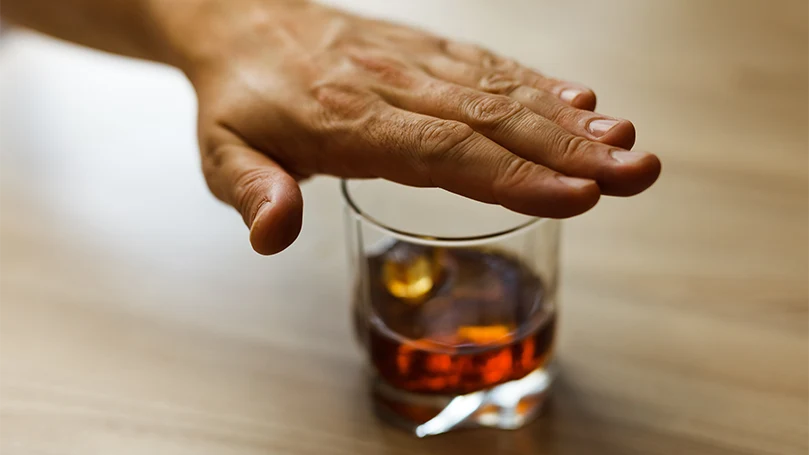 La main d'un homme sur le verre d'alcool.