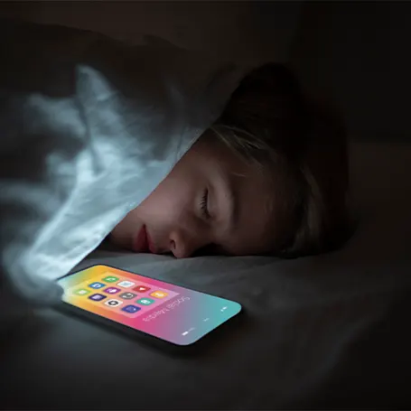 Image d'un enfant dormant à côté d'un téléphone dont l'écran est allumé