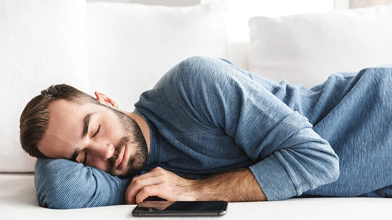 une image d'un homme dormant à côté de son téléphone portable