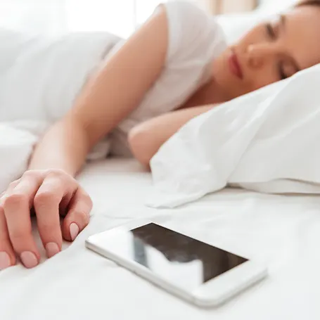 Une image d'une femme dormant à côté de son téléphone