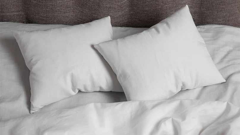 Image de deux oreillers blancs sur un lit.