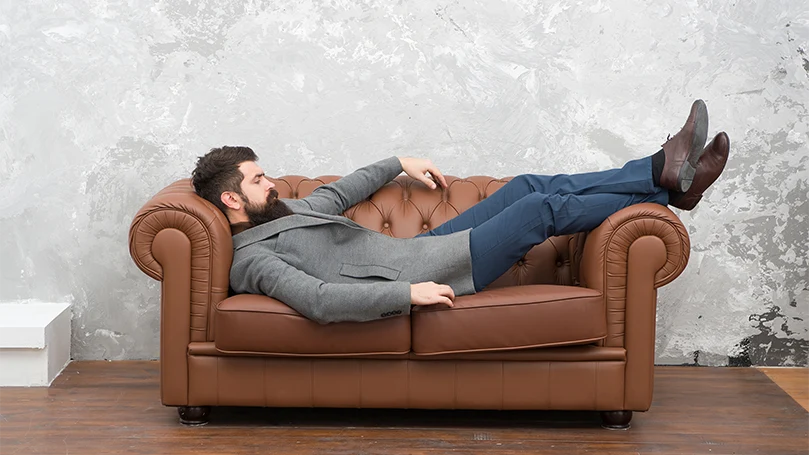 Image d'un homme faisant la sieste sur un canapé.
