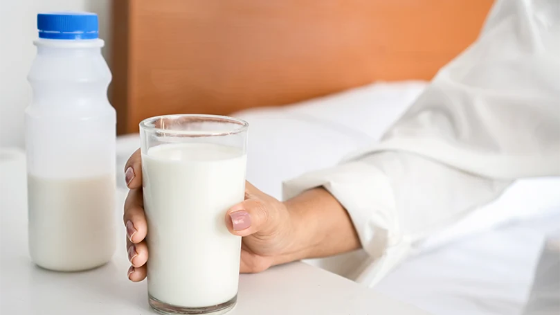 Image d'une femme tenant un verre de lait.