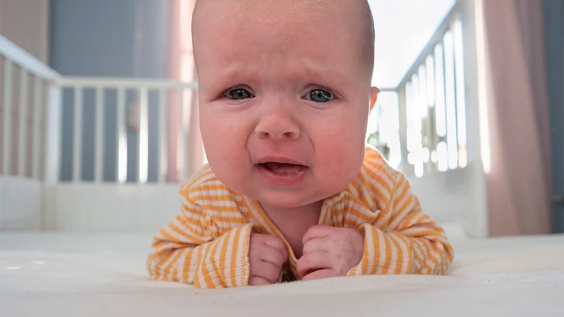 Image d'un bébé pleurant dans un lit d'enfant.