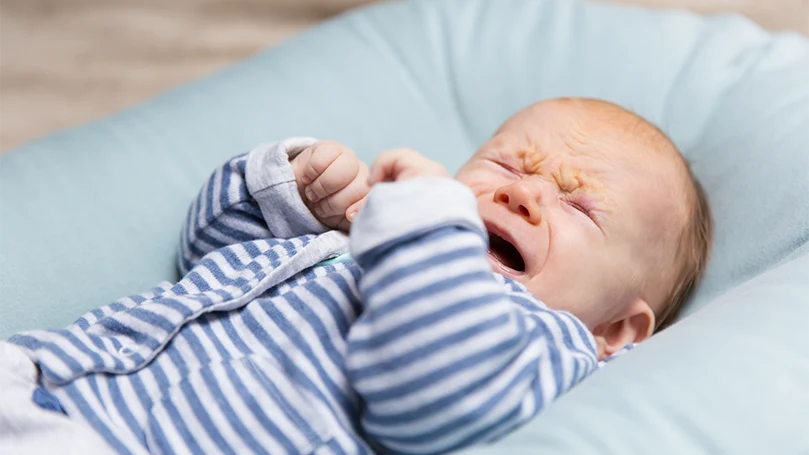 Image d'un bébé pleurant dans un lit d'enfant.