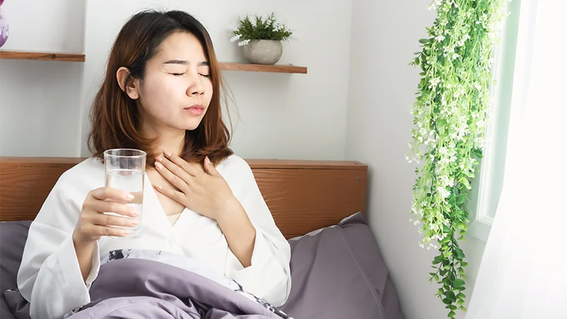 Image d'une jeune femme asiatique malade qui boit de l'eau dans son lit avant de dormir.