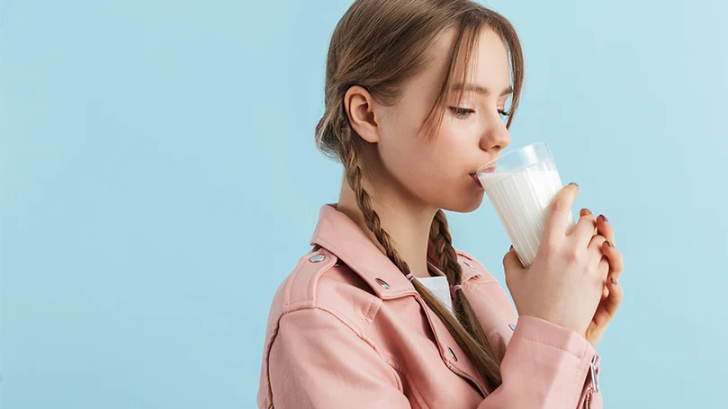 Image d'une jeune femme buvant un verre de lait.