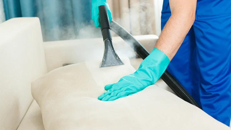 une image d'un travailleur professionnel nettoyant les meubles à la vapeur