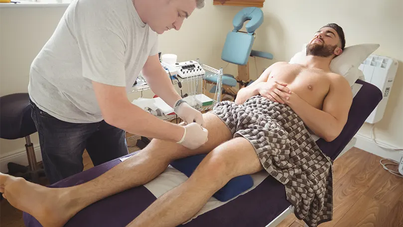 Image d'un homme en thérapie inclinée recevant un massage de la part d'un physiothérapeute.
