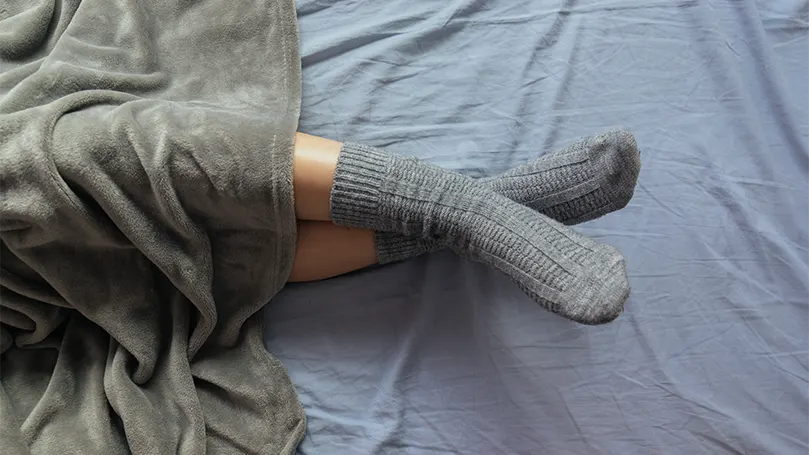 Image d'une femme au lit avec des chaussettes sur les jambes.