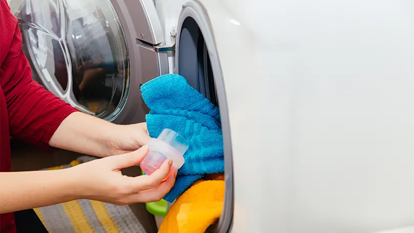 Image d'une femme versant un détergent dans une machine à laver.
