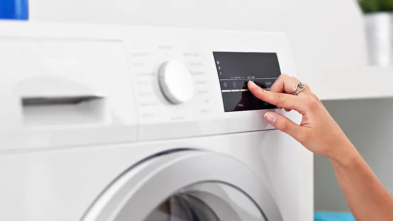 Image d'une femme réglant le séchage à basse température d'une machine à laver.