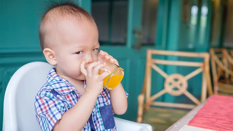 Image d'un bébé de 18 mois qui boit du jus de fruit.