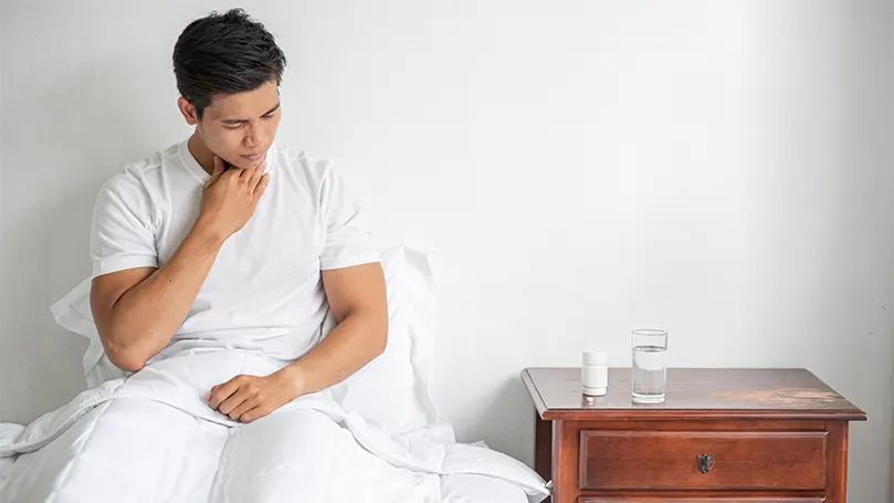 Un homme au lit souffrant de reflux gastro-œsophagien.