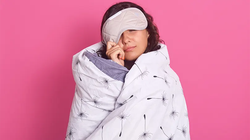 Image d'une femme enveloppée dans une couverture et souffrant d'inertie du sommeil.