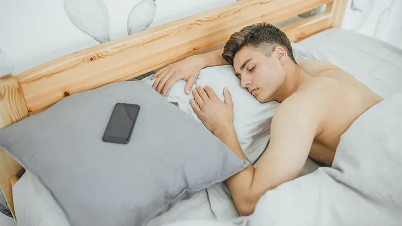 Image d'un jeune et bel homme dormant d'un sommeil profond dans son lit.