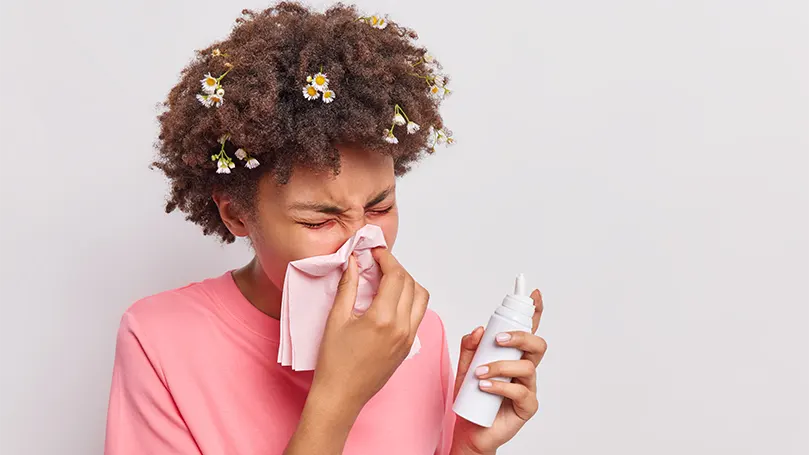 Image d'une jeune femme qui se mouche en raison d'allergies.
