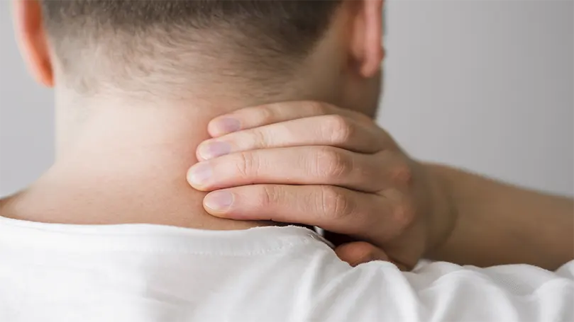 Image d'un homme se tenant le cou en raison de douleurs cervicales.