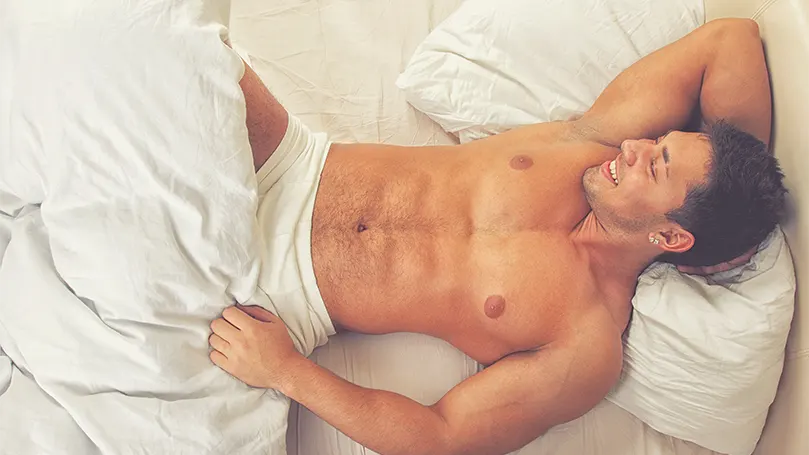 un jeune homme séduisant au lit dans son sous-vêtement