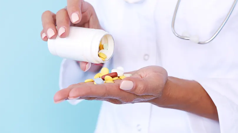 Un médecin prélevant des pilules dans un flacon.