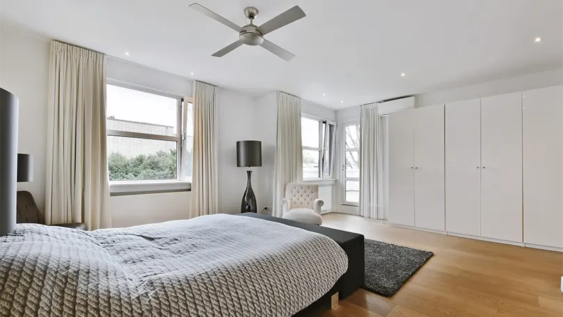 Image d'une chambre à coucher minimaliste avec un ventilateur au plafond.