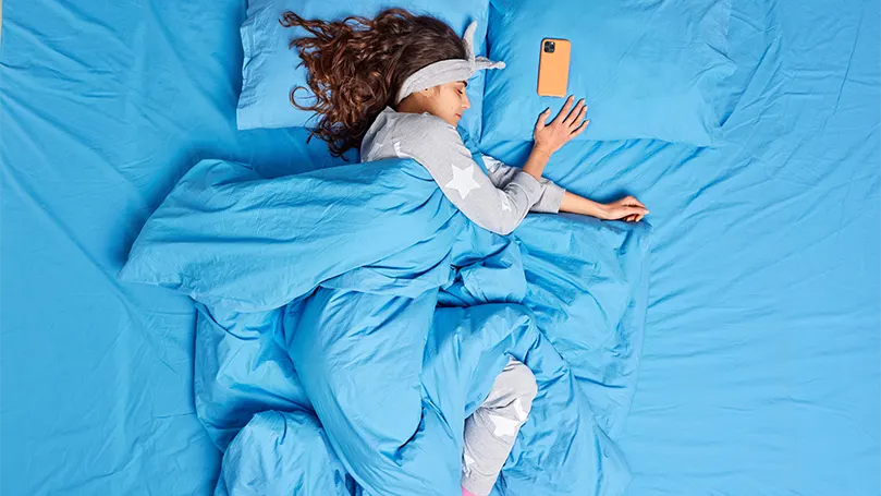 Image d'une femme dormant seule, recouverte d'une couverture.