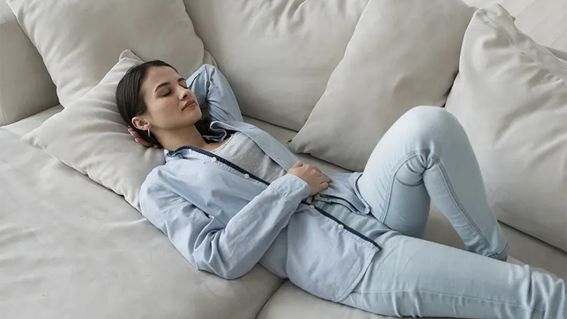 Image d'une jeune femme confortablement allongée sur un canapé.