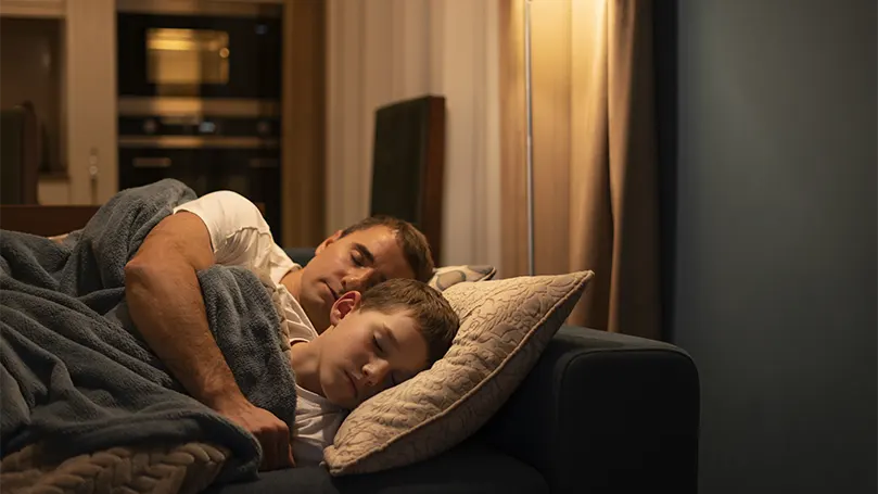 Image d'un père et d'un fils dormant sur un canapé