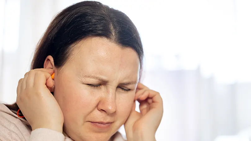 Une femme se tenant les oreilles en raison de problèmes de rupture du tympan.