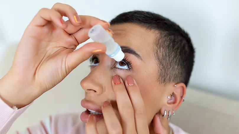 An image of a woman using eye drops.