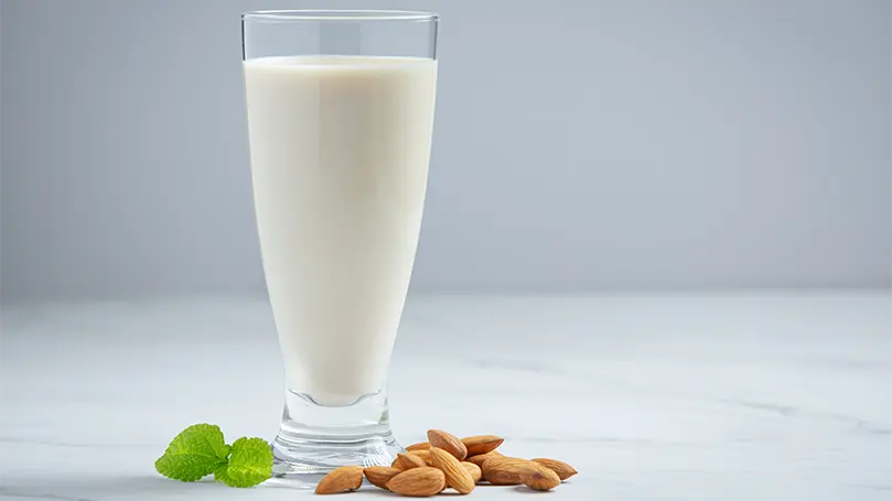 Image de lait d'amande dans un verre avec des amandes sur le côté.