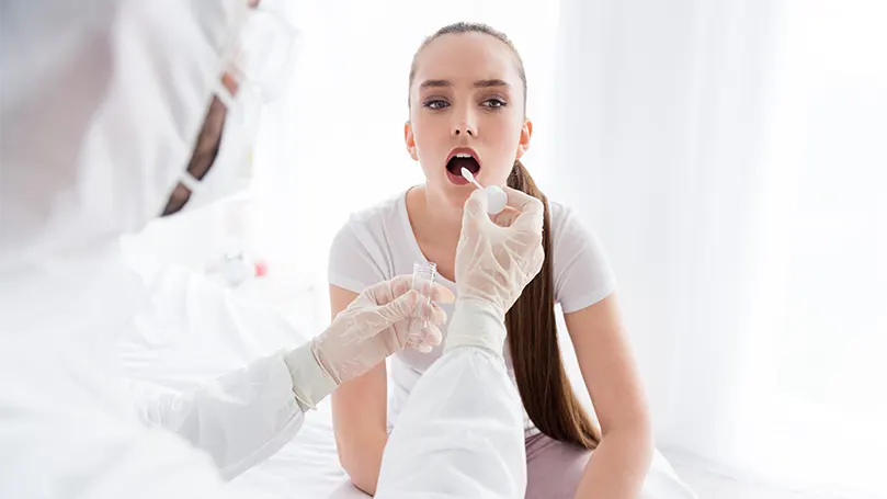 médecin prélevant un échantillon de salive sur une fille