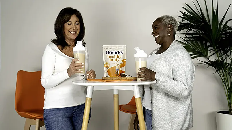 Deux femmes tenant des verres d'horlicks et se tenant à côté d'une table